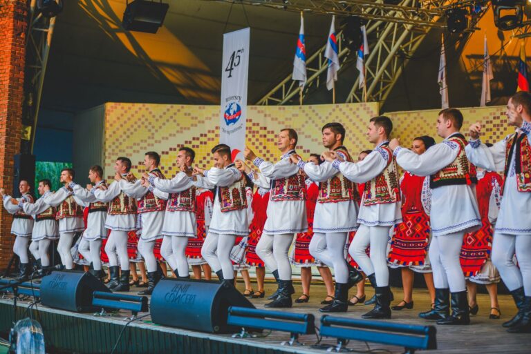 Dansatori în costume populare românești care se prind în horă la o sărbătoare tradițională de sat